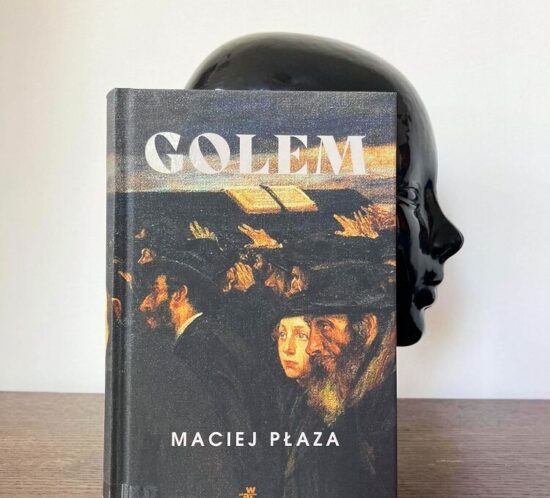 Golem Maciej Płaza. Książka stoi na białym tle, wystaje zza niej rzeźba głowy.